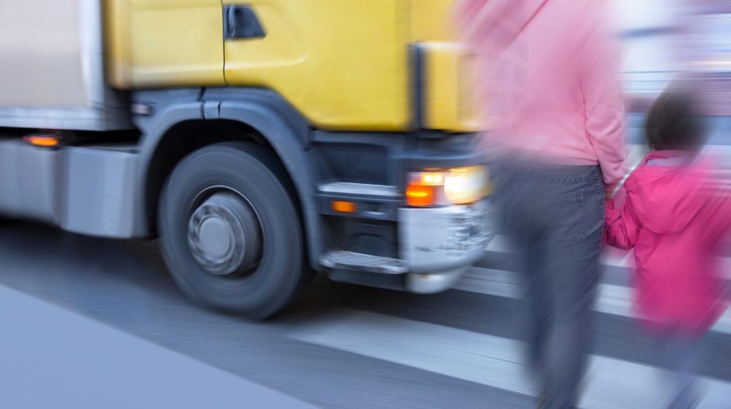 Mother and daughter on pedestrian crossing when big truck is passing
